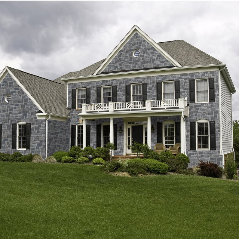 bahamas - Distribution DWP Front view of a two-story stone house with white columns, a balcony, and a green lawn.